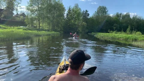 Russia, Gatchina, 29 May 2020: The two young men in a cap float on a kayak on Stock Footage 131402853