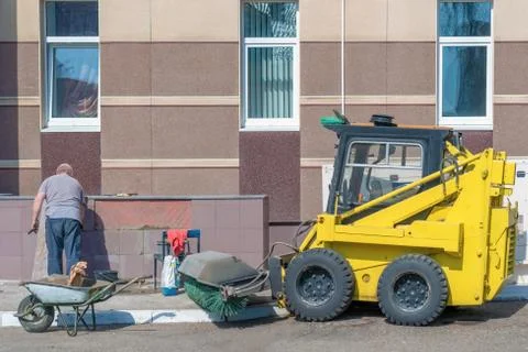 Russia, Kazan - April 12, 2019: An elderly man lays tiles on a wall outside. Stock Photos