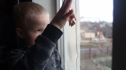 Russian attack on Ukraine. Child sits on the window and cries. Against the backg Stock Footage 171412387