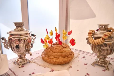 Russian bread ring with rooster lollipops between ornate samovars in warm lig Stock Photos