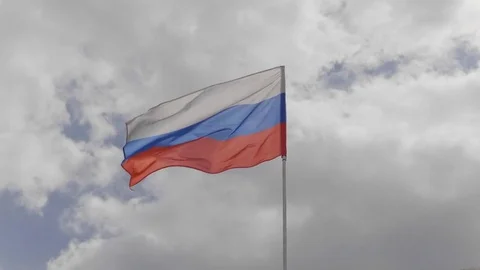 Russian flag on the flagpole waving in the wind against a blue sky with cloud Stock Footage 76756412