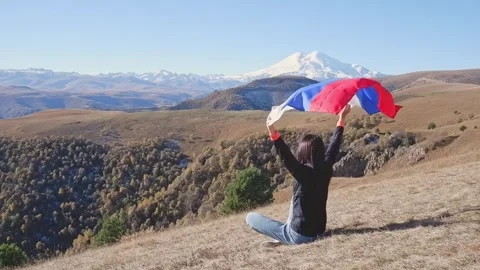 The Russian flag flutters beautifully behind a woman against the backdrop of the Stock Footage 253788489