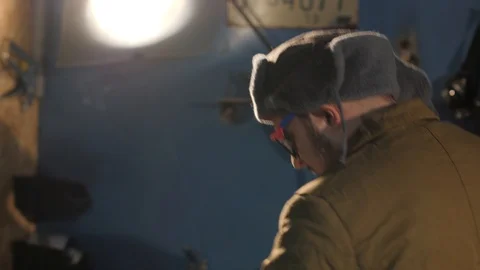 Russian hacker in the hat with earflaps speaks on the phone in the basement. A Stock Footage 107326416