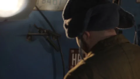 Russian hacker in the hat with earflaps speaks on the phone in the basement. A Stock Footage 107326475