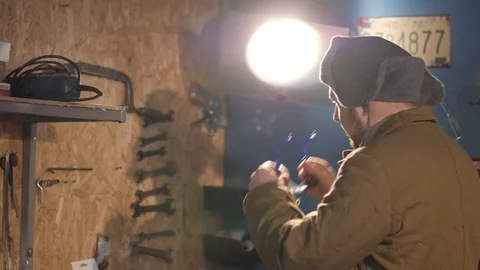 Russian hacker in the hat with earflaps speaks on the phone in the basement. A Stock Footage 107326523
