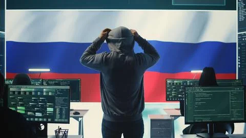 Russian hacker with a hood installing panic by misconception and manipulation Stock Photos