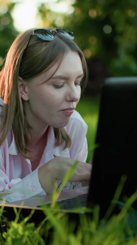 Russian Lady Relaxing on Grass Typing and Eating Apple Outdoors Stock Footage 317582241
