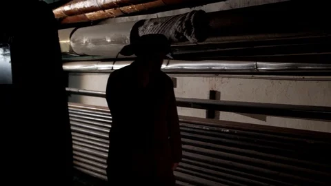 Russian man in a hat with earflaps, talking on the phone in a dark basement and Stock Footage 107324981