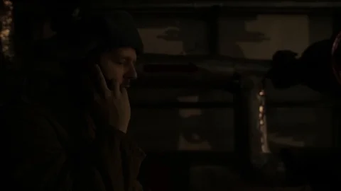 Russian man in a hat with earflaps, talking on the phone in a dark basement and Video stock 107325093