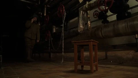 Russian man in a hat with earflaps, talking on the phone in a dark basement and Stock Footage 107325542