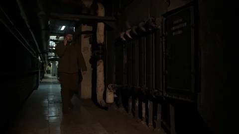 Russian man in a hat with earflaps, talking on the phone in a dark basement and Stock Footage 107325574
