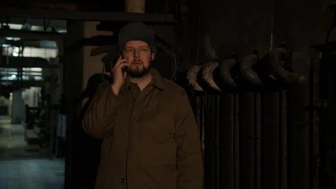 Russian man in a hat with earflaps, talking on the phone in a dark basement and Stock Footage 107325620