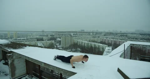 Russian muscular man does push-ups in winter on the roof of a house in moscow Stock Footage 145281557