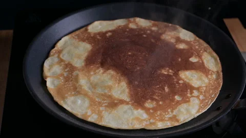 Russian pancake is fried in a pan. The process of making thin pancakes for Stock Footage 151899971