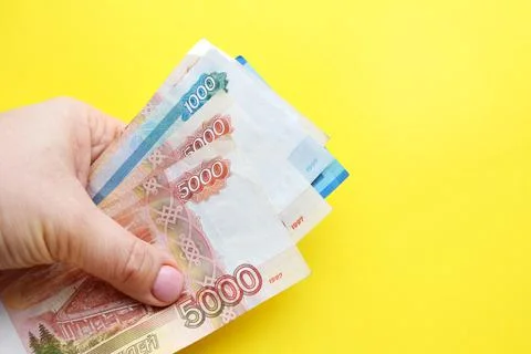 Russian ruble banknotes in a female hand on a yellow background. Copy space. Stock Photos