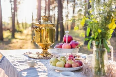 Russian samovar with cups on a table with apples and field flowers bouquet Stock Photos