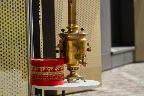 A Russian samovar stands on a table in front of the cafe. Shining on the sun. Stock Photos