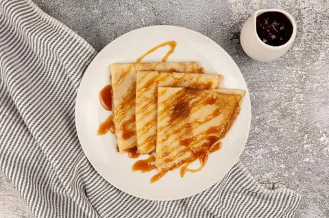 Russian thin pancakes with caramel sauce on a white plate Stock Photos