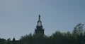 Russian windmill tower behind trees with human figure on top 4k or 4k+ Resolution