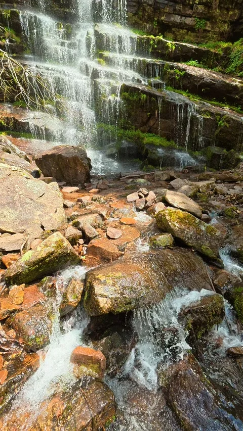 Rust-colored rocks cradle rushing water. Tupavica, Vertical Stock Footage 335947311