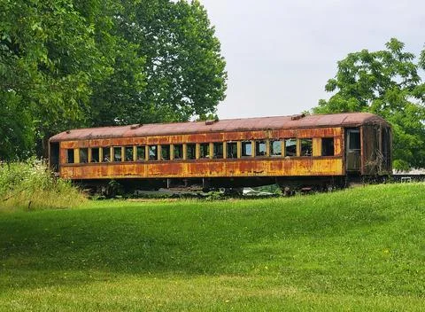Rust-covered abandoned train car with broken windows sitting on grassy grou.. Stock Photos