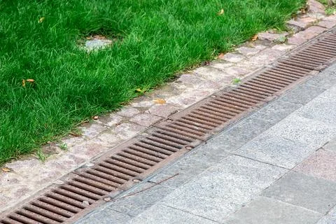 Rust drainage grate of a storm system on a pedestrian sidewalk. Stock Photos