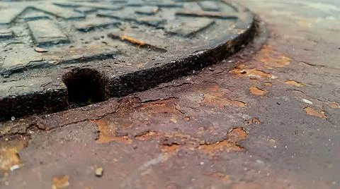 Rust on the floor next to the sewer. Stock Photos
