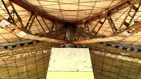 Rusted beams support geometric ceiling over worn outdoor walkway in abandoned Stock Photos