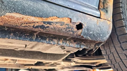 Rusted car sill showing severe corrosion damage and a hole in the metal bodywork Stock Footage 335893456