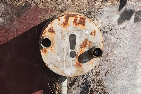 A rusted circular electrical distribution box with an exclamation mark 스톡 사진