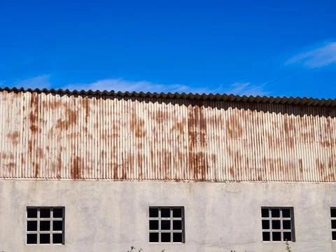Rusted corrugated metal facade and windows under blue sky Foto stock