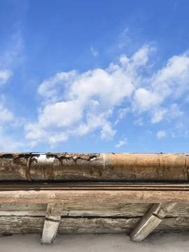 Rusted gutter. Broken gutter on an old roof. Blue sky for copy space on Stock Photos