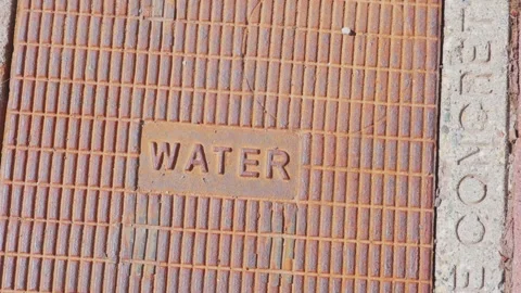 Rusted iron water utility hatch cover on city sidewalk 動画素材 338185085