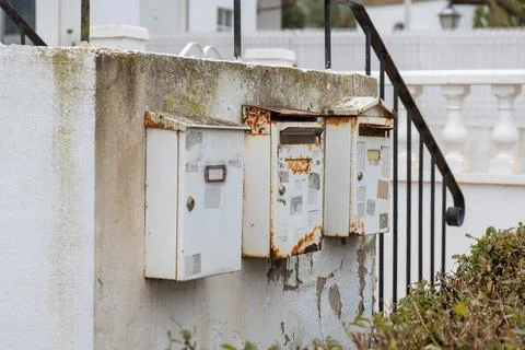 Rusted mailboxes mounted on a weathered wall in Spain, evoke the quiet charm  Foto stock