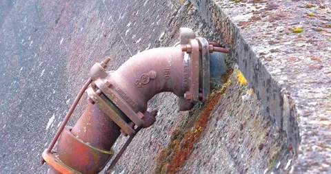 Rusted metal pipe elbow joint mounted on weathered concrete wall Stock Footage 333348164