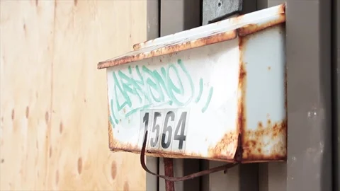 Rusted old beat up rusty worn dented bent white mailbox with green graffiti Stock Footage 251354180