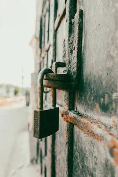 Rusted padlock secures heavy, weathered metal door Stock Photos