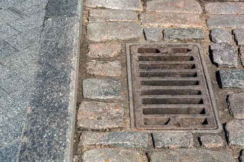 Rusted rectangular grating manhole drainage system on the pavement road. Stock Photos