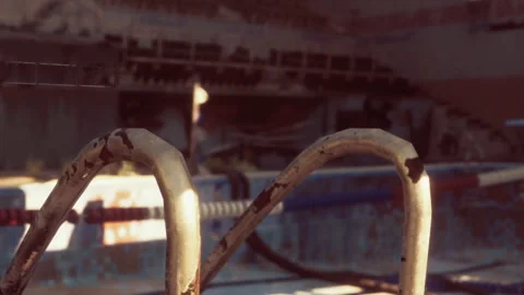 A rusted step ladder stands at the edge of an old swimming pool Stock Footage 344107601