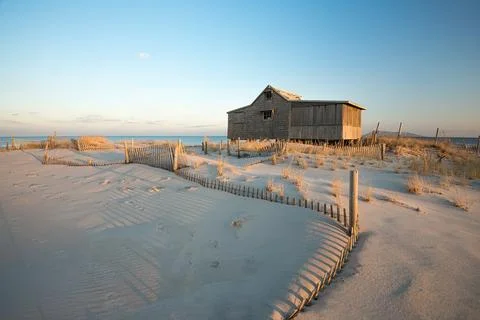 Rustic, abandoned structure on a beach with weathered fencing all around Stock Photos