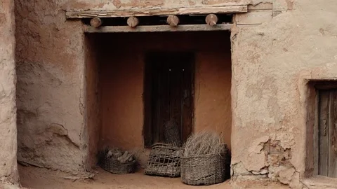 Rustic adobe doorway with woven baskets on dirt ground Видео 347973268
