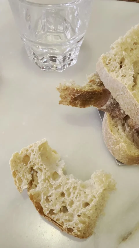 Rustic Artisan Bread and Water Glass on White Table Close Up Vertical Stock Footage 340187836