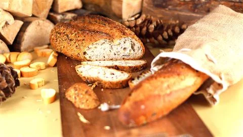 Rustic artisan bread with seeded crust rests on wooden board, surrounded by Stock Photos