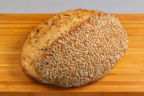Rustic artisan bread sprinkled with sunflower seeds on cutting board Stock Photos