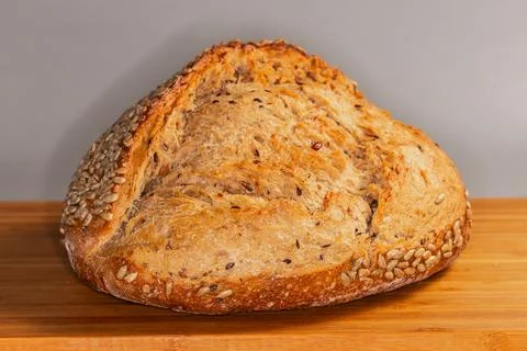 Rustic artisan bread sprinkled with sunflower seeds illuminated from right Stock Photos