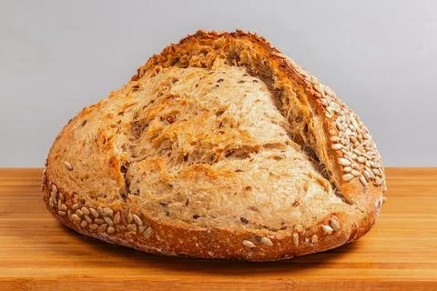 Rustic artisan bread sprinkled with sunflower seeds on cutting board Stock Photos