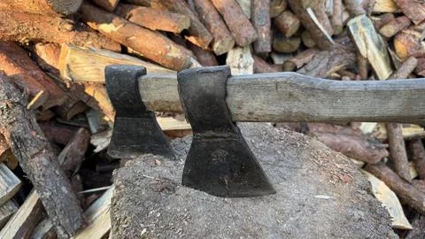 Rustic Axes Embedded in Wood Block with Stacked Firewood Background Stock Photos