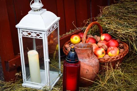 Rustic background, basket with apples, candle and jug on straw. Stock Photos