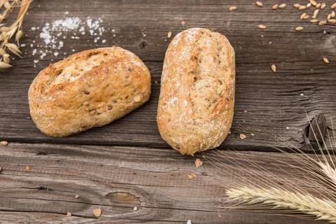 Rustic baguette and wheat on an old vintage planked wood table. Stock Photos