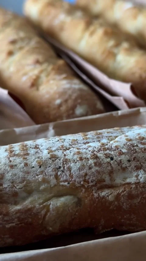 Rustic baked bread loaf with a white powdery coating and small golden-brown Stock Footage 342574809